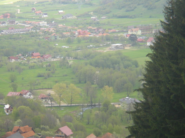 De sus de pe muntele de langa camping. Camingul se vede in centru  langa o cladire in constructie.Se disting rulotele.